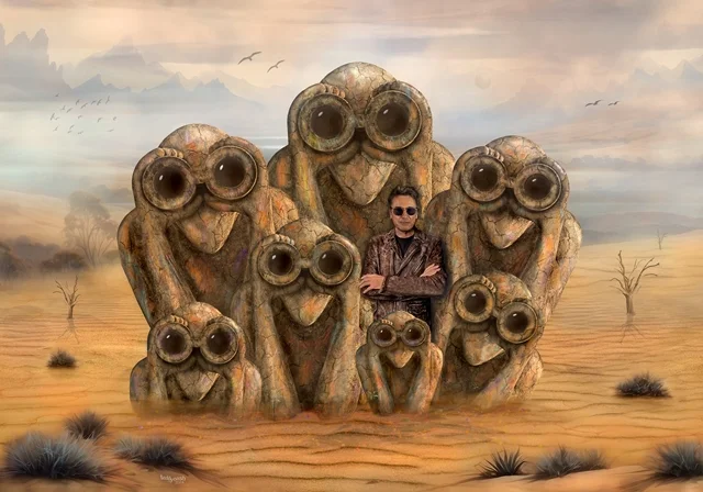 Jean-Michel Jarre in einer surrealen Wüstenlandschaft, umgeben von steinernen Figuren mit großen Fernglasaugen.