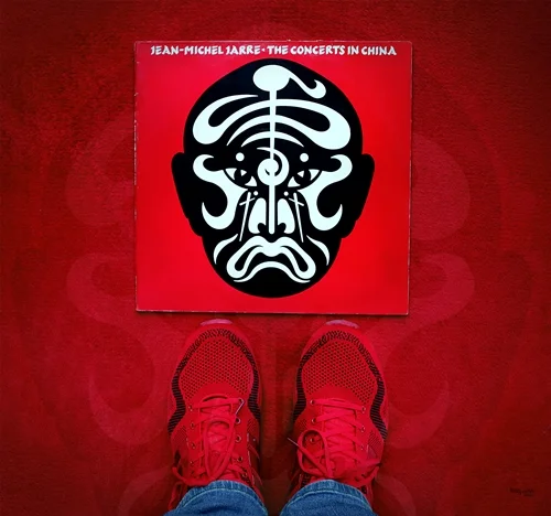 Rote Turnschuhe vor der Schallplatte „The Concerts in China“ von Jean-Michel Jarre. Das Fan-Art-Bild von teddynash spielt mit der Idee einer Reise nach China.
