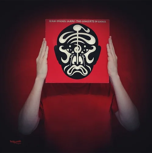 Fan-Art-Fotografie von teddynash: Eine Person hält die Schallplatte „The Concerts in China“ vor das Gesicht, sodass das markante Albumcover die Person vollständig ersetzt. Der rote Hintergrund greift die Farbwelt des Albums auf.