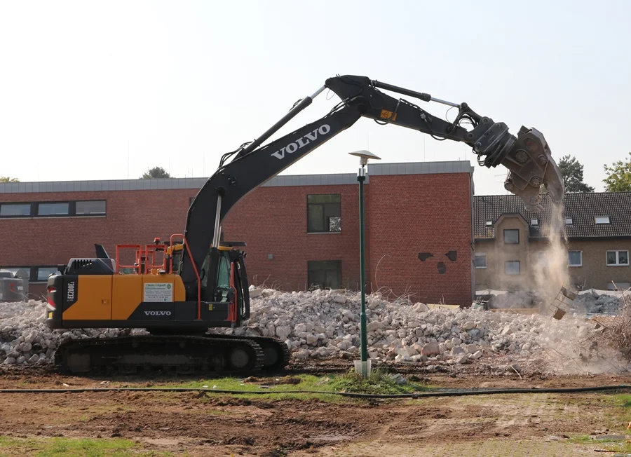 Bagger zerkleinert Betonbrocken auf dem Schulhof Weeze