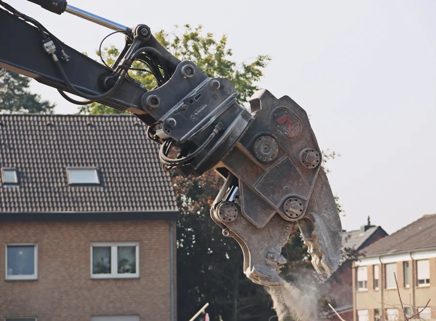 Greifarm vom Bagger zerdrückt Betonklotz