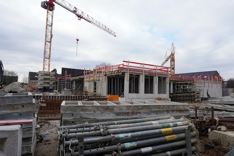 Der Rohbau der neuen Petrus-Canisius-Grundschule in Weeze wächst weiter. Im Vordergrund liegen Baumaterialien und Gerüstteile.