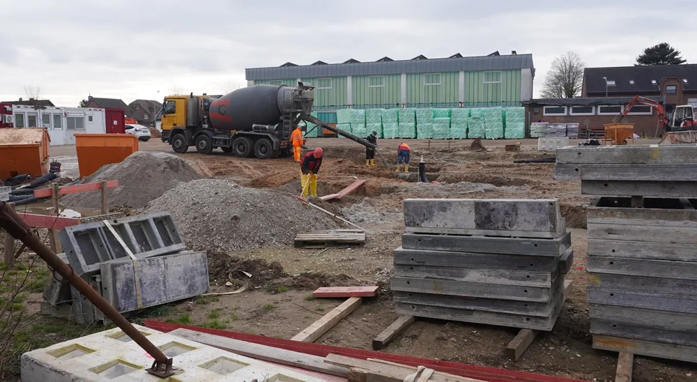 Vorbereitungen für den Bau der neuen Mensa an der Petrus-Canisius-Grundschule in Weeze. Arbeiter und Betonmischer sind auf der Baustelle im Einsatz.