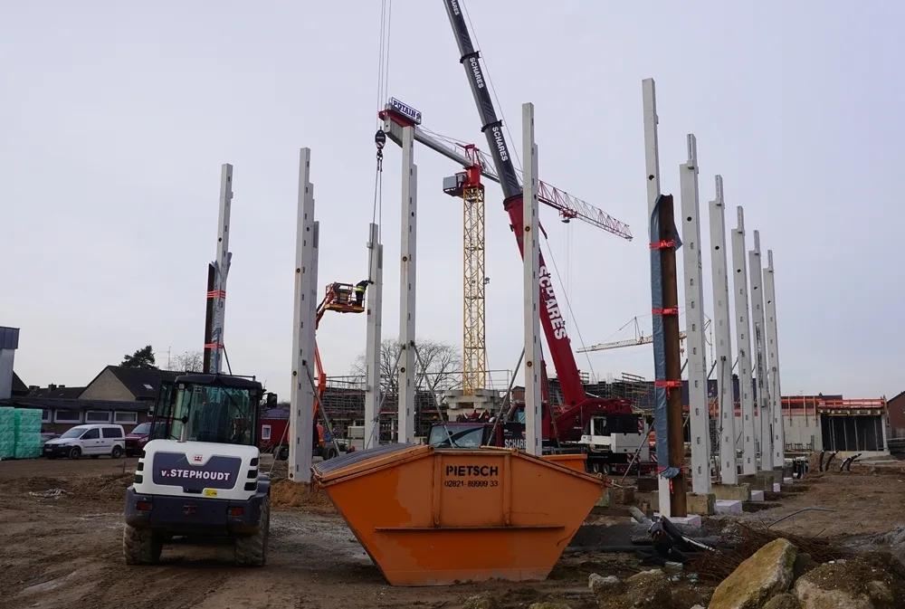 Die Stahlkonstruktion der neuen Schulmensa an der Petrus-Canisius-Grundschule in Weeze wird aufgebaut. Große Betonstützen stehen bereits auf der Baustelle.
