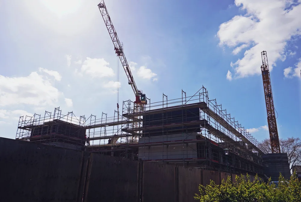 Seitenansicht der neuen Petrus-Canisius-Grundschule in Weeze mit Baugerüsten und zwei großen Baukränen.