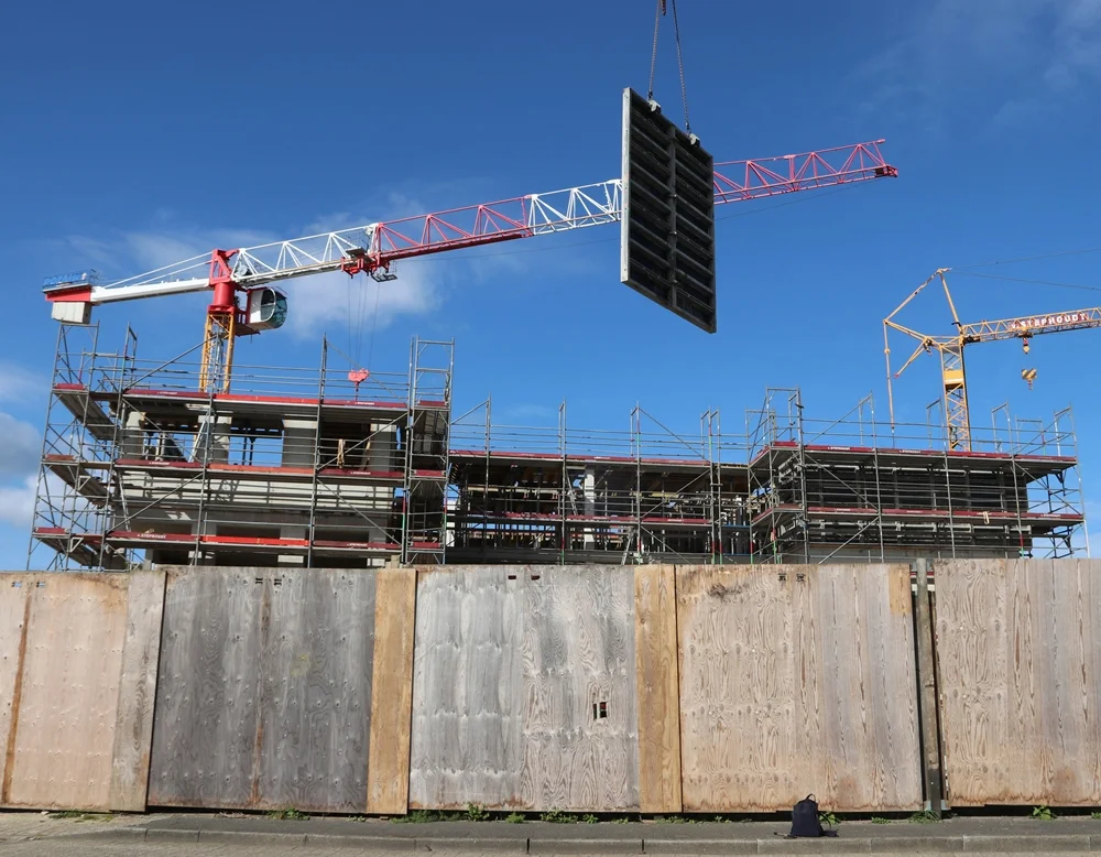 Ein Kran hebt eine große Wandschalung über die Baustelle der neuen Petrus-Canisius-Grundschule in Weeze