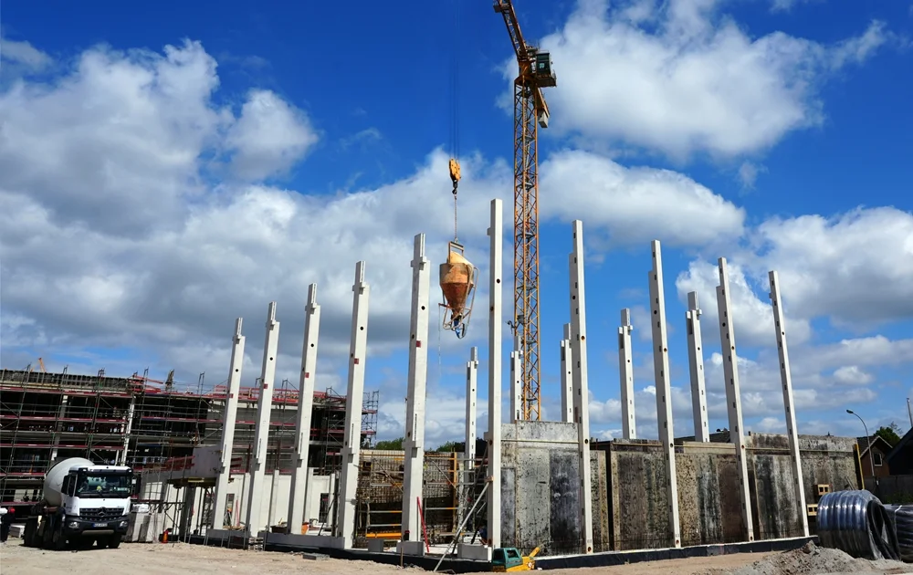 Die neue Schulmensa in Weeze wächst weiter – ein Kran bewegt Material zwischen hohen Betonstützen
