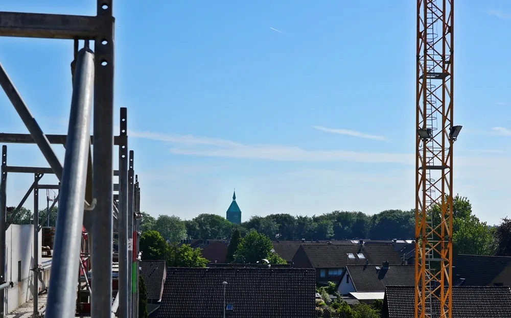 Zwischen Baukran und Gerüst taucht in der Ferne der Kirchturm von Weeze auf