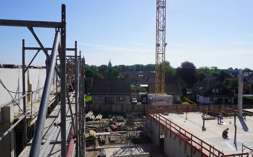 Zwischen Gerüst und Neubau taucht in der Ferne erneut der Kirchturm von Weeze auf