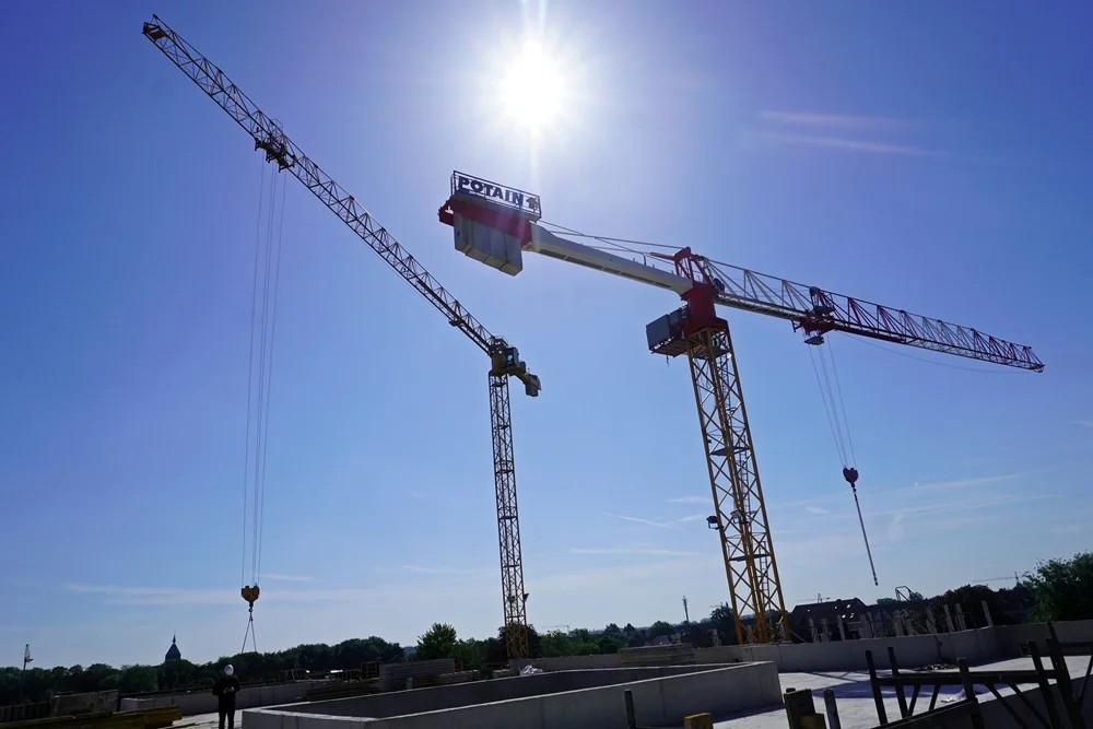 Die Baukräne der neuen Petrus-Canisius Grundschule in Weeze ragen im hellen Sonnenlicht über die Baustelle hinaus