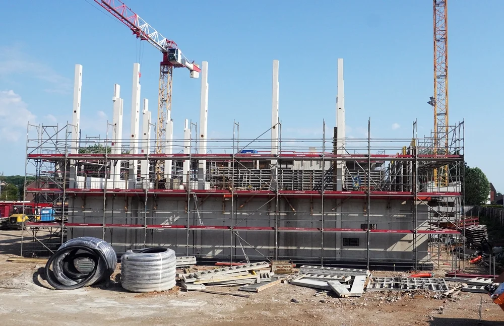 Rohbau der neuen Schulmensa in Weeze mit weißen Betonstützen, Gerüsten und Baukränen auf der Baustelle im Juni 2026.