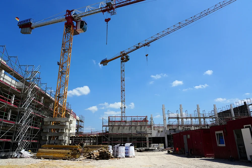 Baustelle der neuen Schule in Weeze mit zwei Baukränen, Gerüsten und dem Rohbau des modernen Schulgebäudes im Juli 2026