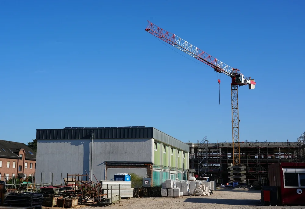 Panoramablick über die Baustelle mit Kran und alter Sporthalle der Hauptschule im Juli 2026.
